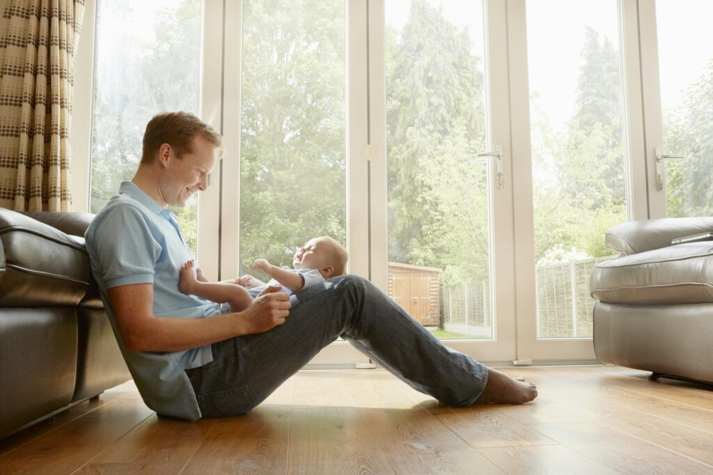 Mature man sitting on floor with baby son on his lap